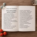 Open book with a table of contents for appetizer recipes on a wooden surface.